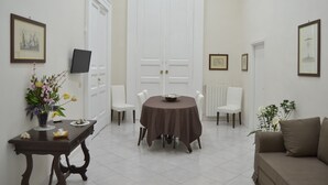 A dining area with a round table, chairs, a sofa, and a TV on a stand. - Comfortable apartment in the historic center of Naples close to everything (Napoli)