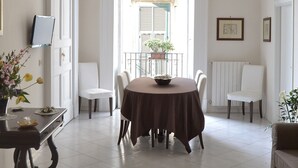 A dining area with a round table, chairs, a TV on the wall, and a view of the outside balcony. - Comfortable apartment in the historic center of Naples close to everything (Napoli)