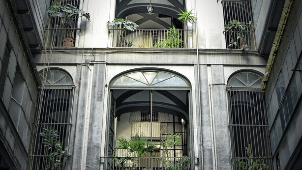 A multi-story building with arched windows and balconies, featuring plants and a central archway. - Comfortable apartment in the historic center of Naples close to everything (Napoli)