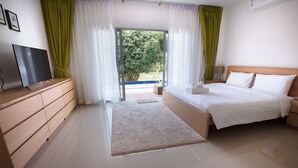 Un dormitorio con una cama, un televisor sobre una cómoda y vistas al exterior.