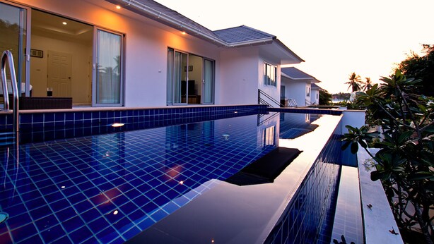 Una casa moderna con piscina, ventanas amplias y un balcón.