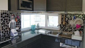 Una cocina moderna con encimera negra, microondas integrado y ventana que proporciona luz natural.