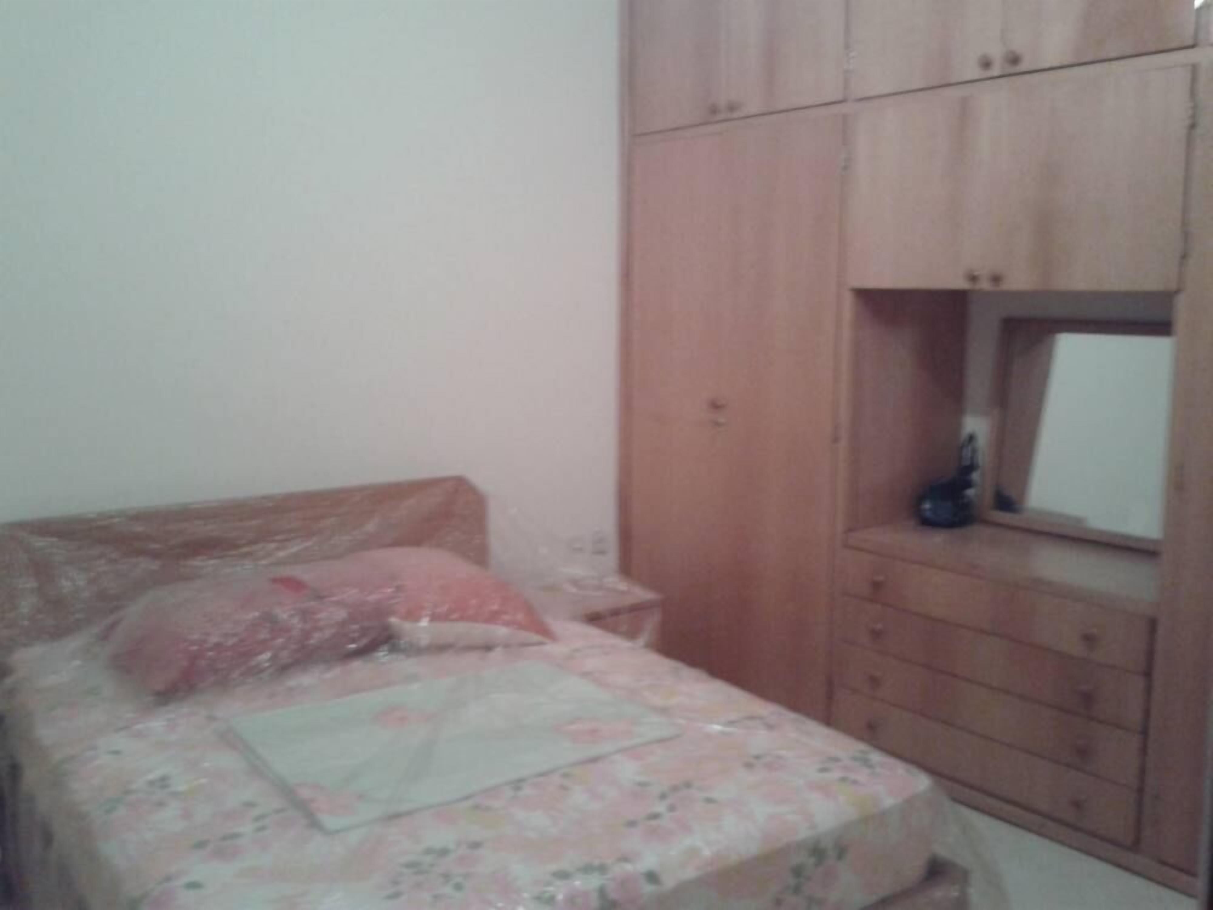 Une chambre à coucher avec un lit, une armoire en bois et une petite fenêtre.