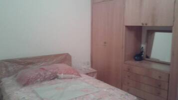 Une chambre à coucher avec un lit, une armoire en bois et une petite fenêtre.