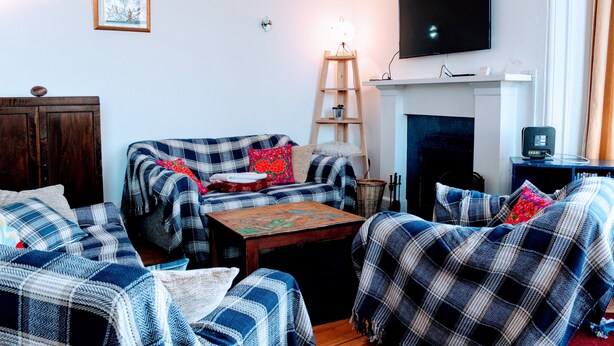 A living room with a sofa set, a fireplace, a television mounted on the wall, and a wooden ladder.