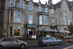 Un bâtiment historique sur lequel on peut lire l’inscription « BLACK IVY », indiquant qu’il s’agit d’un pub doté d’un bar, d’une salle où l’on sert de la bière à la pression et d’une terrasse.