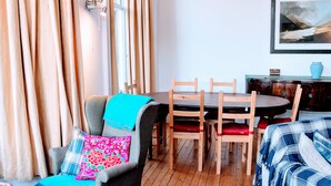 A cozy room with a dining table, chairs, a sofa, and a painting on the wall.