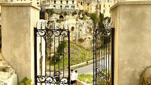 A gated entrance with a road leading to a cliffside building complex.