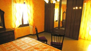 Un dormitorio con cama, una silla, cómoda, espejo y armario.