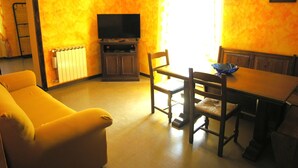 Una sala de estar con sofá, una mesa de comedor con sillas, televisor y radiador.
