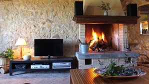 Una chimenea de piedra con fuego, un televisor y una mesa de madera con un plato decorativo.