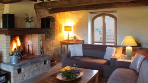 Una sala de estar acogedora con chimenea de piedra, vigas de madera, un sofá y una mesa con un plato decorativo.