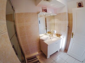 A bathroom with a white sink, mirror, and vanity, beige tiled walls, and a white door. - Large 45m2 south-facing apartment with beautiful terrace, enclosed garden, magnificent view! (Sainte-Maxime)