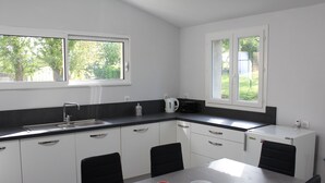 Une cuisine moderne avec des meubles blancs, un plan de travail noir et une table à manger agrémentée de quatre tasses rouges.