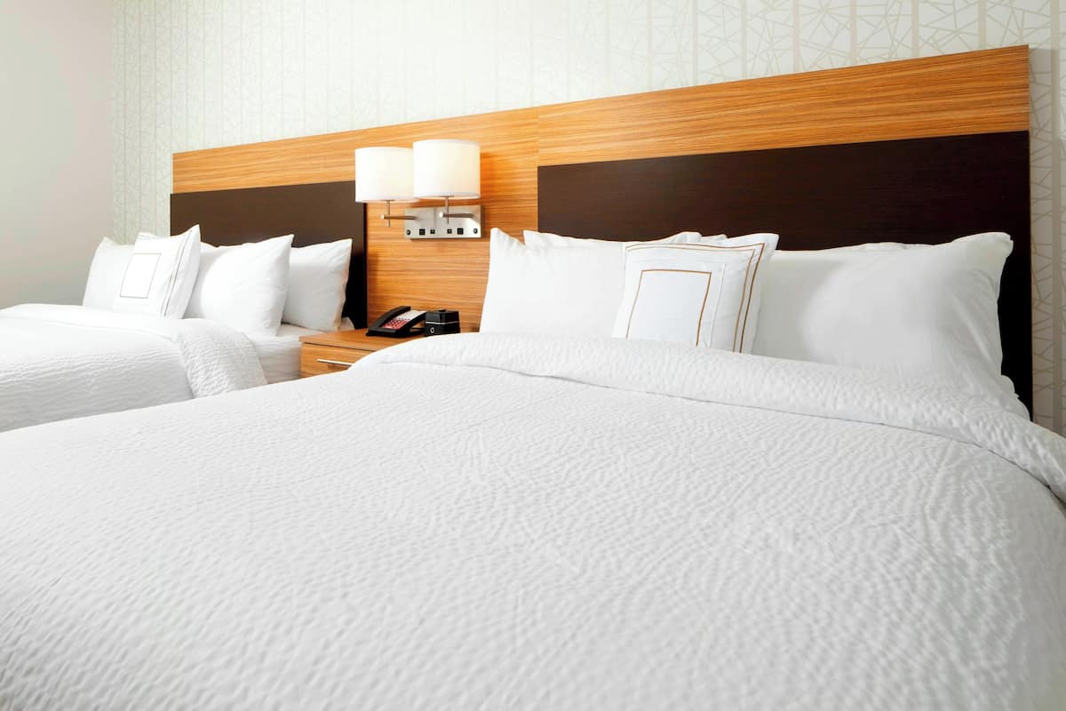 A hotel room with a large bed, two bedside tables, and a nightstand with a lamp.