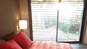 A bedroom with a large bed, red pillows, a bedside lamp, and a window with blinds. - Loft on Mont St Clair with private pool and sea view - SETE (Sète)