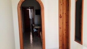 A hallway with a tiled floor, wooden doors, and a white bench.