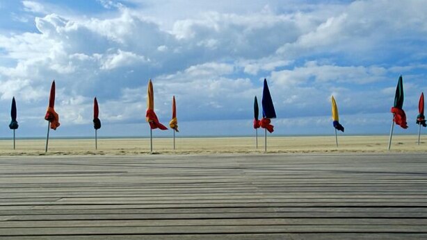 A wooden boardwalk leading to a beach with flags in various colors. - Game room, fireplace and garden! (Le Faulq)
