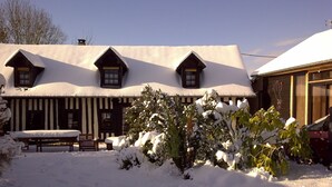 A traditional chalet with a snow-covered roof and a wooden exterior. There is a bench and a small table in the foreground, and a car parked to the right. - Game room, fireplace and garden! (Le Faulq)