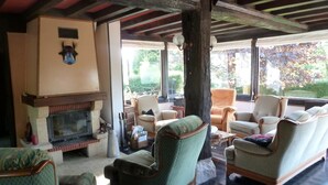 A cozy living room with a fireplace, comfortable seating, and a view of the outdoors. - Game room, fireplace and garden! (Le Faulq)