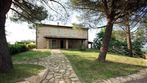 A stone house with a stone pathway leading to the entrance, surrounded by trees and a grassy area. - Splendid private villa for 12 people with swimming pool and olive trees (Gualdo Cattaneo)