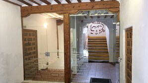 A hallway with a wooden ceiling, a glass door with a reflection, and a staircase with a yellow railing.