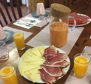 Ett frukostbord med tallrikar fyllda med ost och charkuterier, en kanna med juice och en kaffekanna.