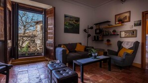 A cozy living room with a sofa, armchairs, a coffee table, and a view through a large window.