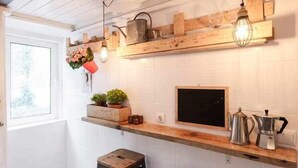 Una cucina con scaffali in legno, una macchina da caffè e un lampadario.