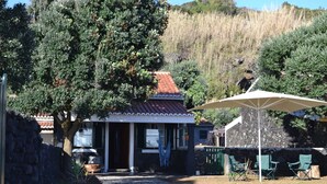 Une maison avec un toit en tuiles, une véranda et un espace salon extérieur.