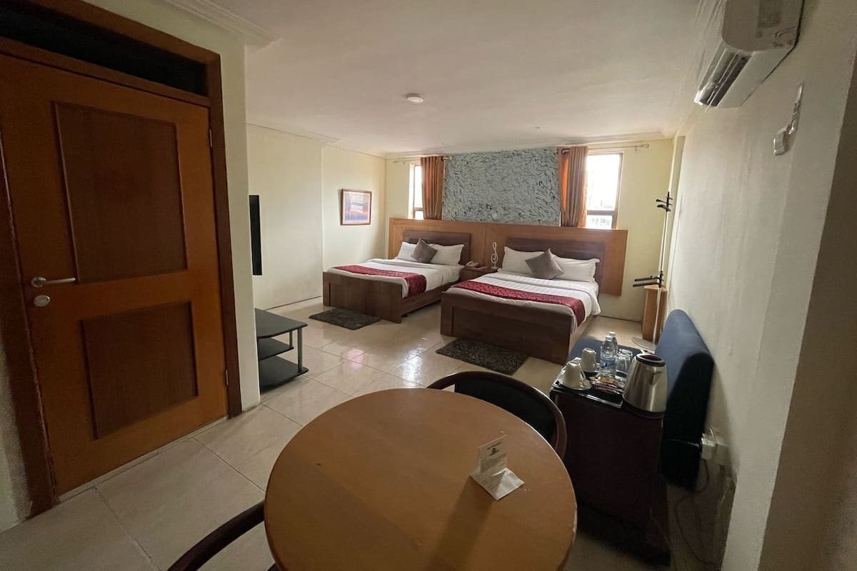 Une chambre d’hôtel avec deux lits simples, une table ronde, un petit bureau et une chaise.