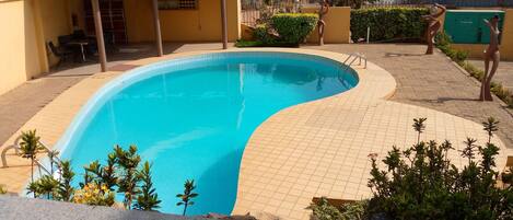 Una piscina al aire libre, sombrillas, sillones reclinables de piscina