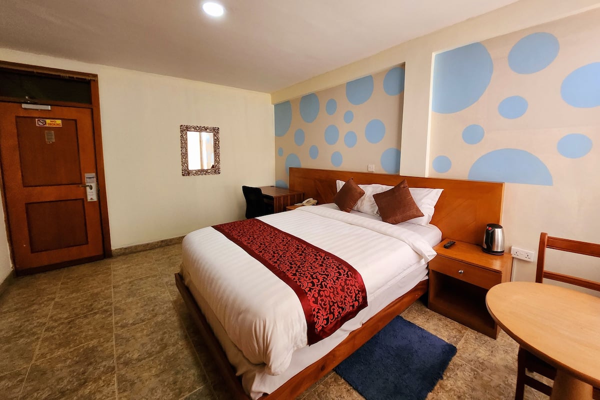 Une chambre d’hôtel avec un lit, une table de chevet, une chaise et une petite table.