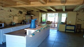 A kitchen with a central island, stone walls, and a view to the outside.