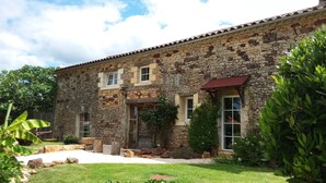 A stone building with a tiled roof, a front door, and windows.