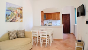 Un espacio habitable compacto con kitchenette, comedor y sofá.