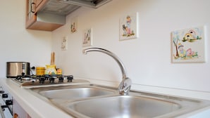 Una cocina con estufa a gas, dos fregaderos y obras de arte colgadas en la pared.