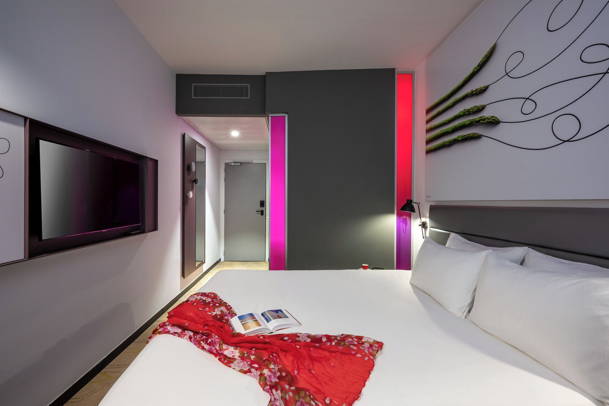 Une chambre d’hôtel moderne dotée d’un grand lit, d’un téléviseur à écran plat, d’une table de chevet et d’une œuvre d’art accrochée au mur.