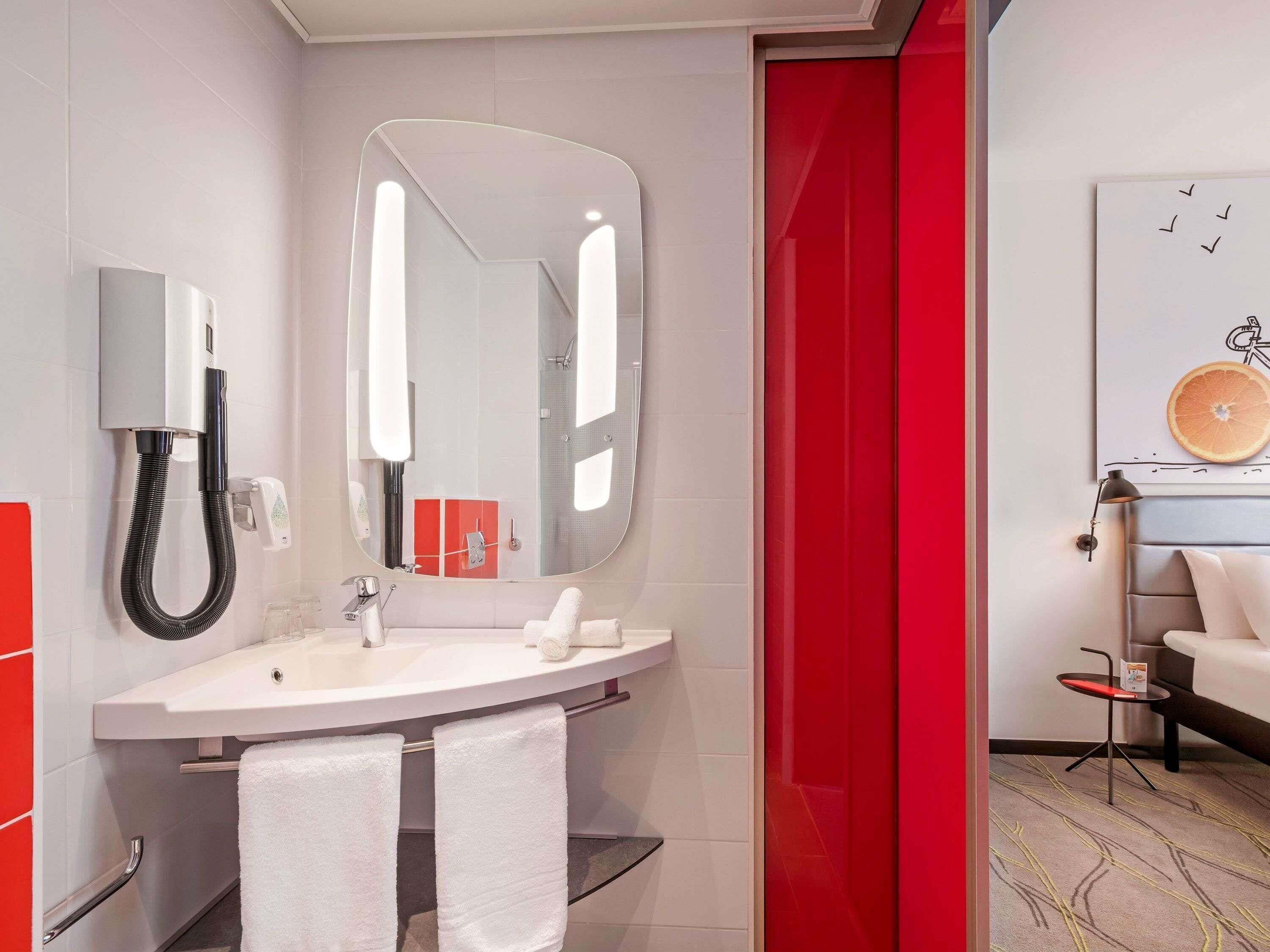 A modern bathroom with a large mirror, a sink, and a shower.