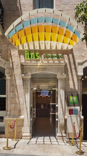The entrance to ibis Styles Hotels with a modern design, featuring a colorful awning and a reception area with a digital display. - ibis Styles Jerusalem City Center - An AccorHotels Brand (Jerusalem)