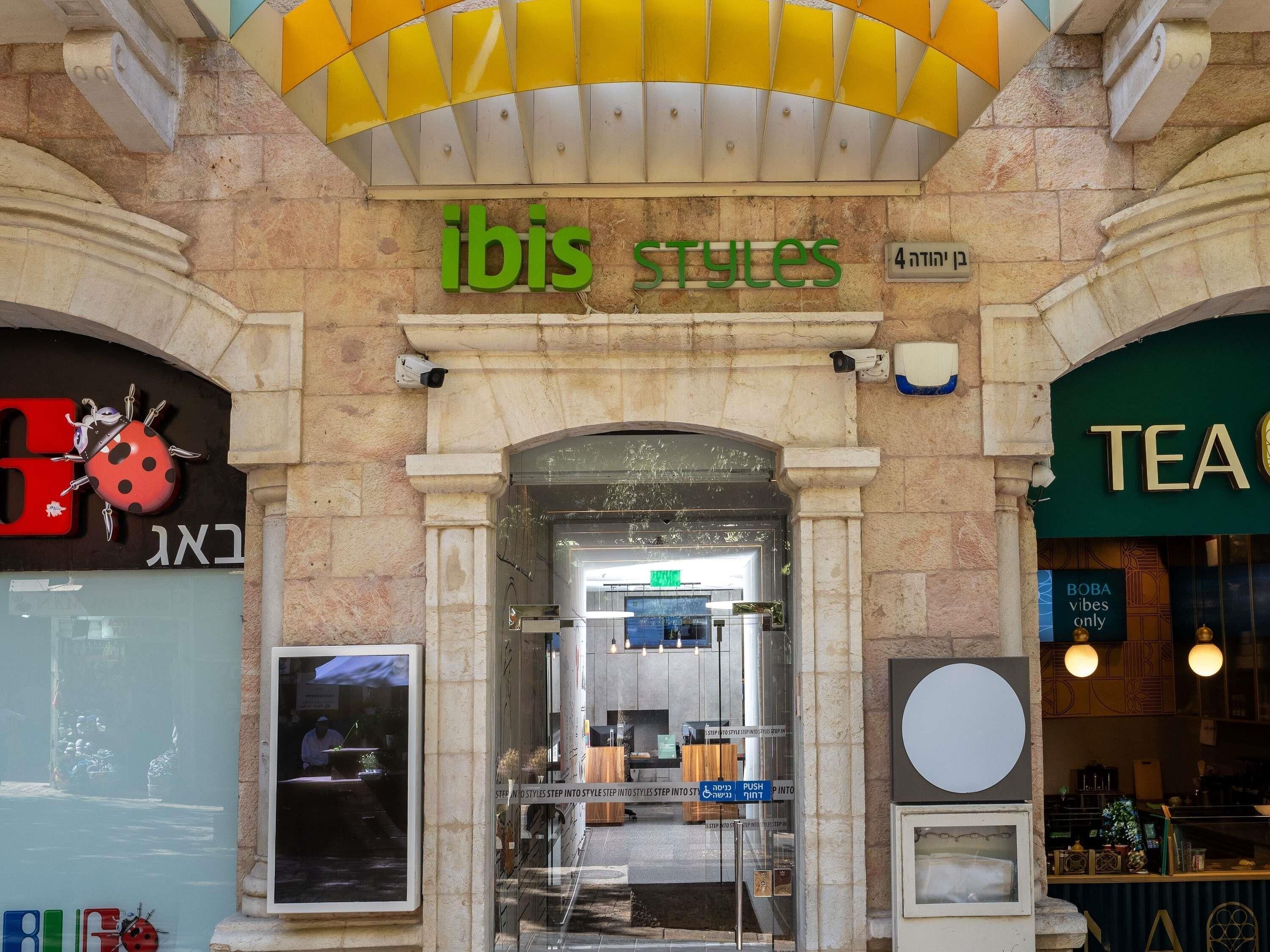 Fachada de una tienda con un letrero que dice 'ibis STYLES' y una entrada visible.