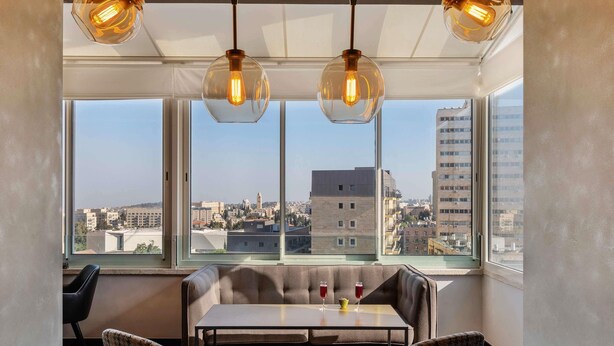 A modern room with a large window, a table, two chairs, and a hanging light fixture. - ibis Styles Jerusalem City Center - An AccorHotels Brand (Jerusalem)