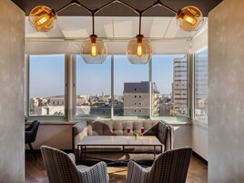 Una habitación moderna con un ventanal grande, una mesa, dos sillas y una lámpara colgante.