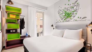 A modern hotel room with a bed, a wall-mounted shelf unit, a window with a view, and a wall art piece.