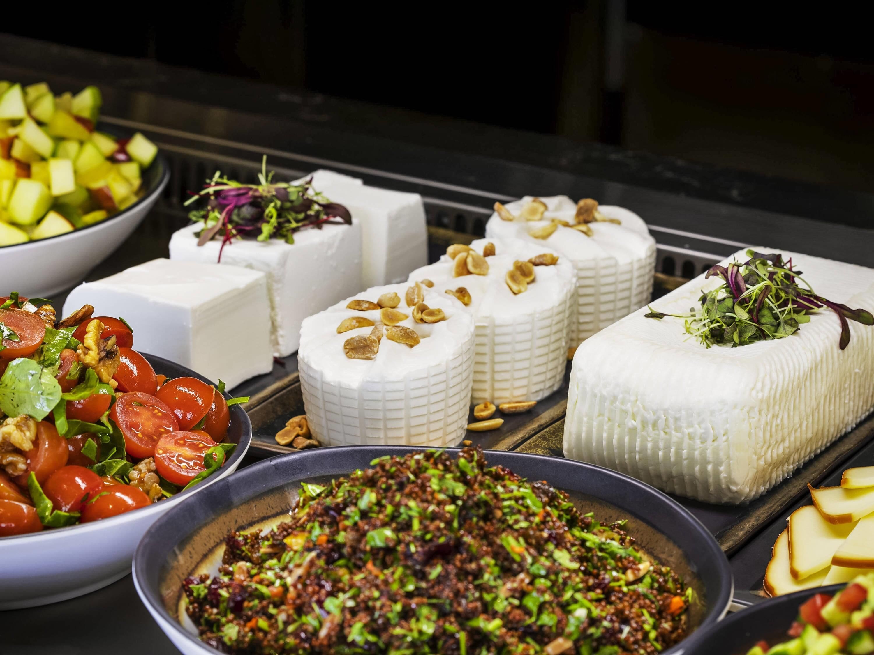 Variedad de alimentos, incluyendo queso, ensalada y un plato con vegetales picados.