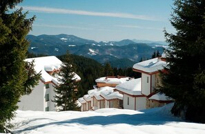 Surrounded by evergreen trees, this mountain resort offers a serene escape amidst rolling hills and distant mountains.