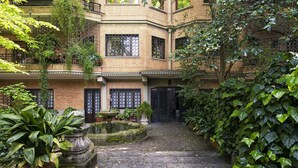 Une cour avec une fontaine, des plantes en pot et un bâtiment doté de nombreux balcons et fenêtres.