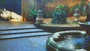 Une cour avec une fontaine en pierre, un mur en briques et un sol carrelé.