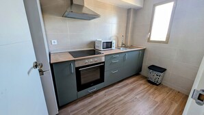 Une cuisine compacte équipée d’un four à micro-ondes, d’une cuisinière et d’un évier.