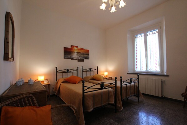 A bedroom with a bed, bedside table, lamp, and a window with curtains.